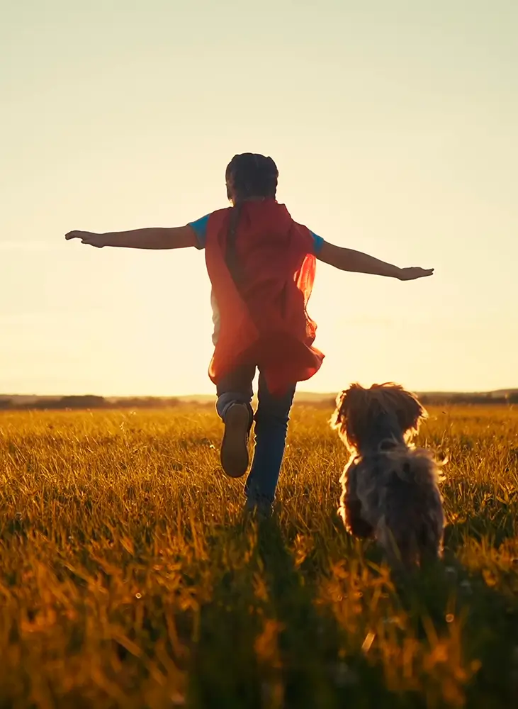 A child and a dog enjoying running on a grass field, reflecting a sustainable ecosystem